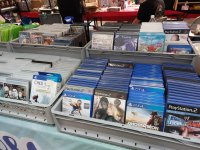 Diverse Videospielverpackungen aufgereiht auf einem Stand bei der Vienna Comix, darunter Spiele für PlayStation 2, PlayStation 3, PlayStation 4 und Wii U.