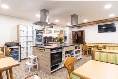 Moderne Küche mit zentralem Kochbereich, Esstischen und Schränken im Hotel in Sölden, Tirol.