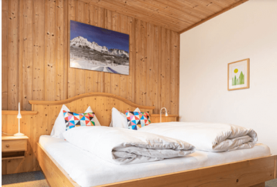 Doppelzimmer mit Holzwänden, einem großen Bett und bunten Kissen in einem Hotel in Sölden, Tirol.